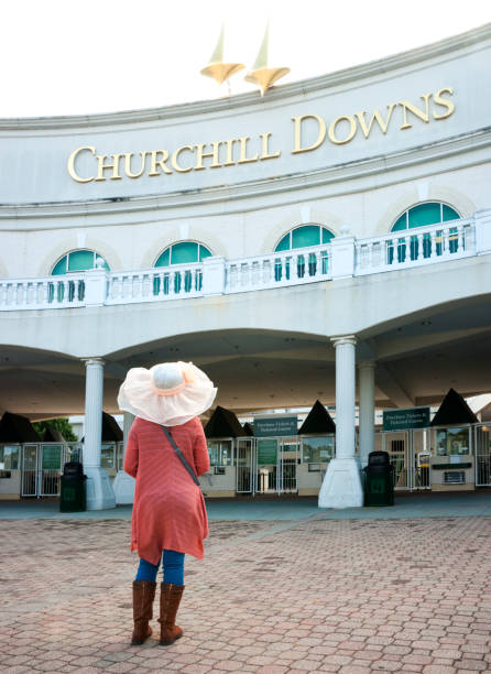 Visiting Churchill Downs Louisville, KY, USA - October 12, 2015: A female tourist wearing a wide brimmed Derby hat walks toward the exterior entrance of the Churchill Downs Museum to learn about the Kentucky Derby. kentucky derby stock pictures, royalty-free photos & images