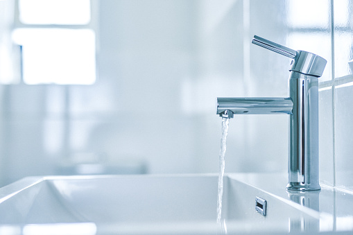 Shot of an open tap with running water in a bathroom at home