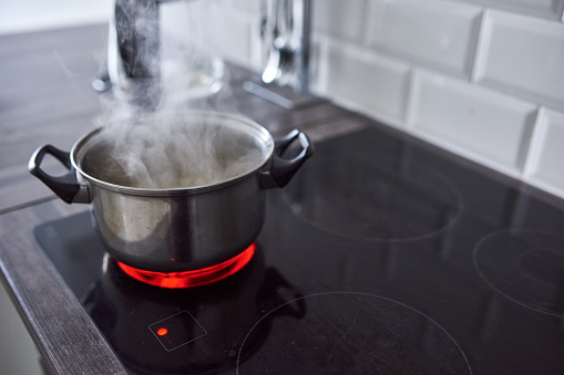 Shot of water boiling in an open pot on a hot stove at home
