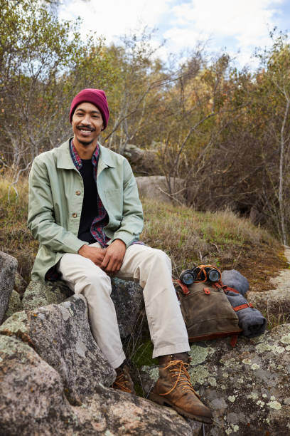 istock Smiling young man sitting on a rock while out hiking 1182177637
