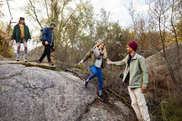 istock Young man helping a friend down some rocks while hiking 1182177863
