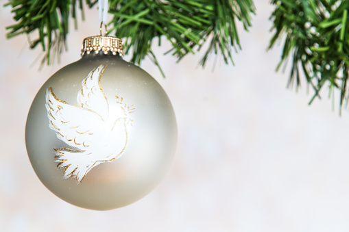 Silver Christmas decoration bauble ball with peace dove and pine decorations. Copy Space