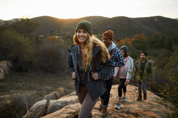 smiling young woman and friends hiking up a hill together - nature forest clothing smiling imagens e fotografias de stock