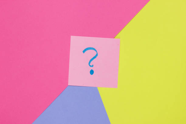 istock Memo piece of paper with drawn question marks on colored  background. Top view. Minimalism 1182181859