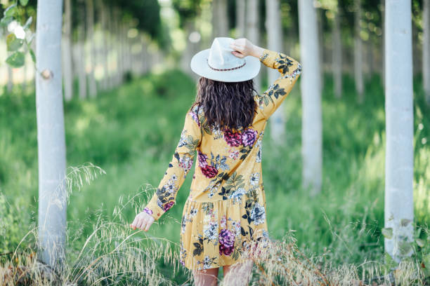 Rear view of hiker young woman, wearing flowered dress, hiking in the countryside.