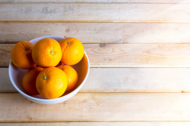 istock Fresh oranges in white bowl on wood table. With copy space for text or design. 1182185377