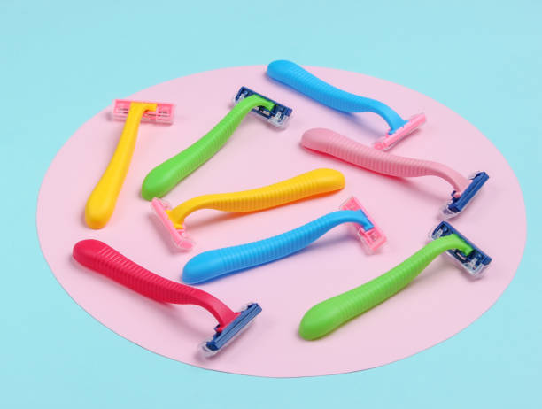 istock Many colored plastic razors on blue background with pink pastel circle. Minimalistic beauty still life 1182188192