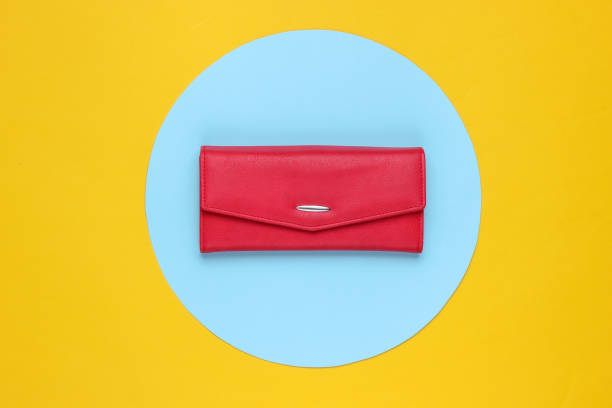 istock Stylish women's red leather wallet on yellow background with blue pastel circle. Creative minimalistic fashion still life 1182188202