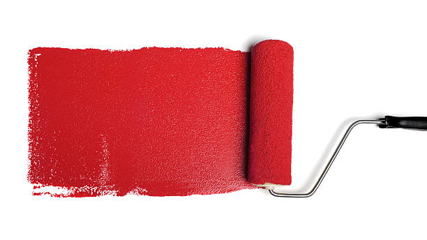 Roller with red paint on a white wall stock photo