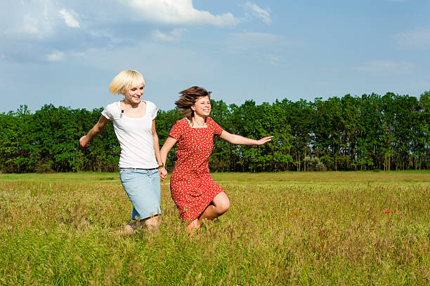 Two girls are running in a meadow stock photo