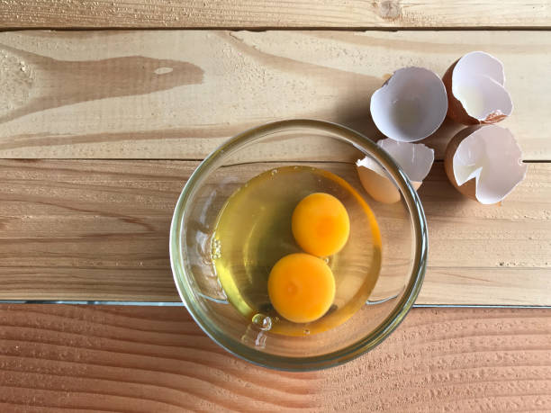 istock two fresh yolk and egg white in clear glass cup and four eggshells beside it 1182190576