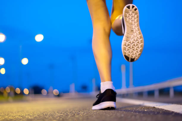 istock Movement. Woman legs running on asphalt road. 1182190738