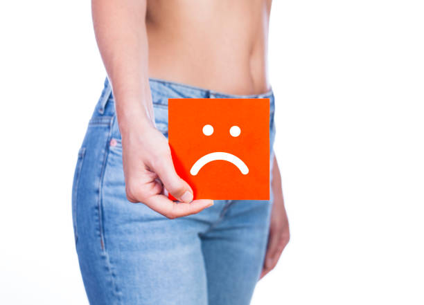 Vaginal or urinary infection and problems Young woman holding a paper with sad smiley face on her waist. Vaginal or urinary infection and problems concept demobilization photos stock pictures, royalty-free photos & images
