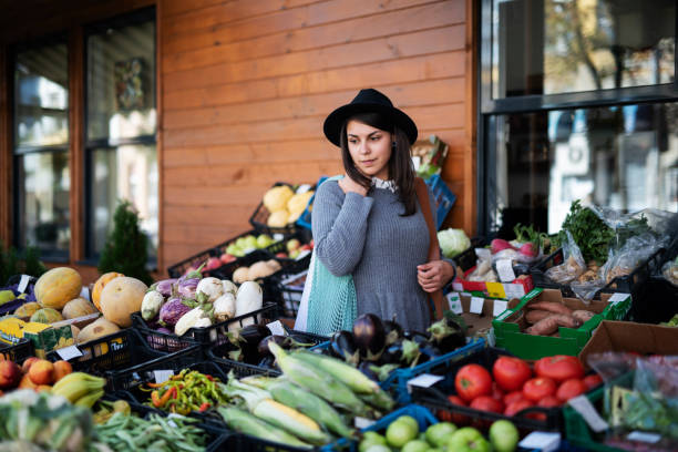 Young woman buying fruit and vegetables at outside market, she looking away.