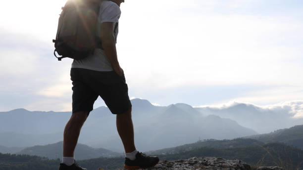 istock Male hiker relaxes above hillside at sunrise 1182202646