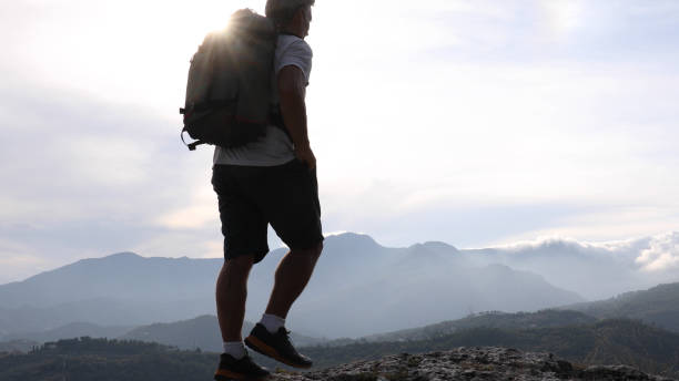 istock Male hiker relaxes above hillside at sunrise 1182202701
