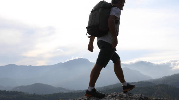 istock Male hiker relaxes above hillside at sunrise 1182202703