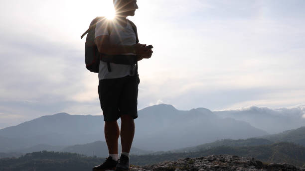 istock Male hiker relaxes above hillside at sunrise 1182202746