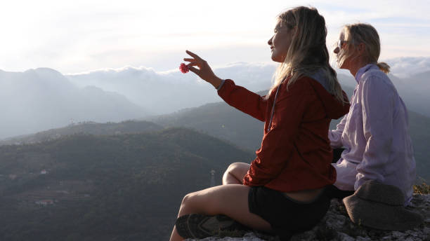 istock Female hikers relaxes on cliff above hillside below 1182202819