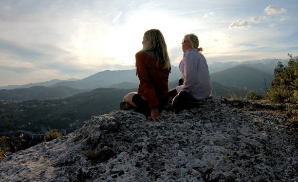 istock Female hikers relaxes on cliff above hillside below 1182202930