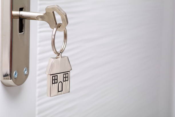 Home key with metal house keychain in keyhole stock photo