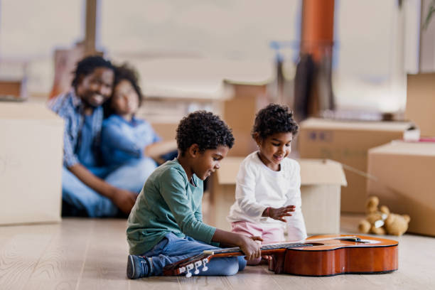 istock Happy black siblings playing a guitar into their new apartment. 1182204842