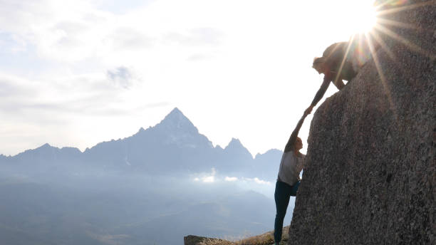 istock Mountaineer offers partner a helping hand at sunrise 1182205872