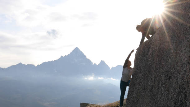 istock Mountaineer offers partner a helping hand at sunrise 1182205878