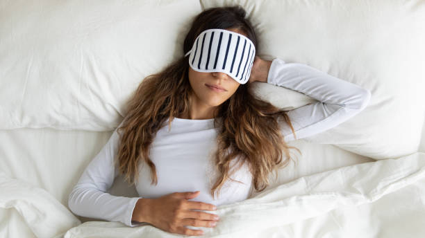 calma tranquilla giovane donna di razza mista che indossa la maschera addormentata, sognando. - sheet women bed sleeping foto e immagini stock
