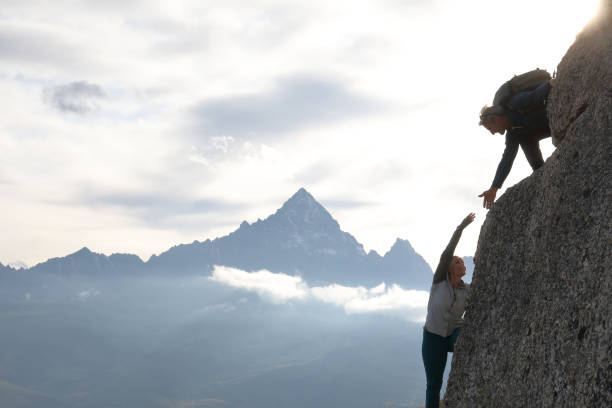 istock Mountaineer offers partner a helping hand at sunrise 1182206008