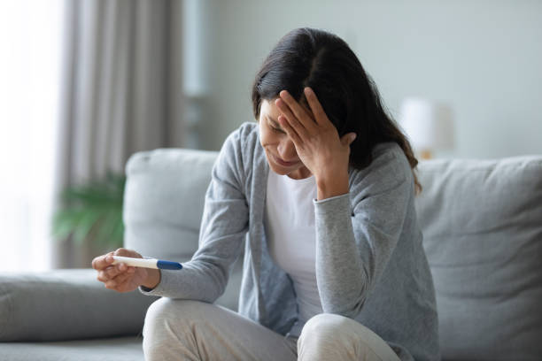 Stressed biracial young girl worrying about unwished pregnancy. Frustrated unhappy mixed race woman sitting in living room, holding quick plastic test, worrying about unwished pregnancy. Stressed biracial young girl dissatisfied with negative result at home. unwanted pregnancy stock pictures, royalty-free photos & images