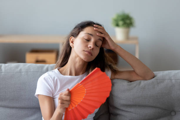 Overheated young girl cooling herself, feeling uncomfortable.