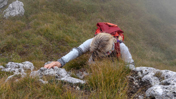 kobieta alpinistka scrambles w górę trawiastego klifu - scrambling zdjęcia i obrazy z banku zdjęć