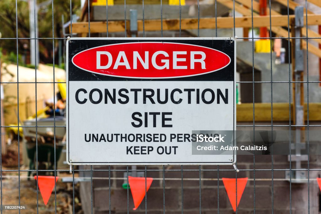 Construction site sign A 'Danger, Construction site, Unauthorised Persons Keep Out' sign mounted on a wire fence in front of a building site Construction Site Stock Photo