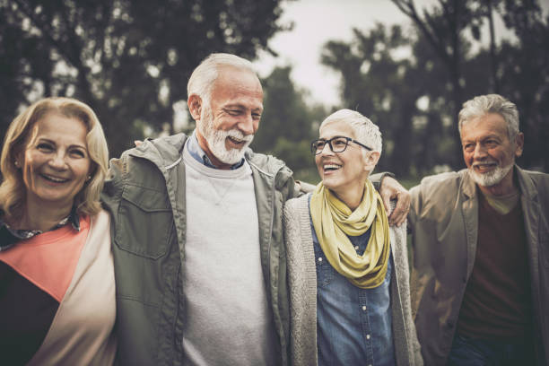 istock Group of happy senior friends communicating while taking a walk in the park. 1182209968