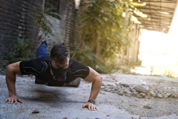 muscular man wearing sport mask and doing push-ups outdoors. - exercising men push ups muscular build imagens e fotografias de stock