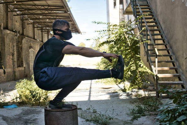 Muscular man standing with one leg on bin.