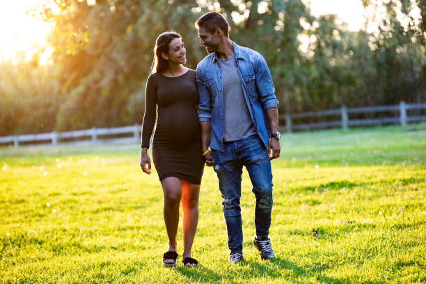 beautiful pregnant couple relaxing with a walk in the park at sunset. - couple human pregnancy sunset walking imagens e fotografias de stock