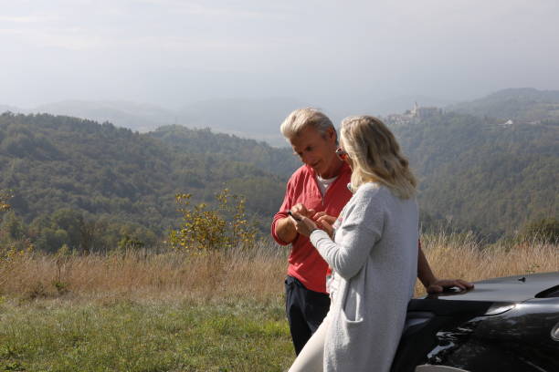 istock Couple relax against car while finding directions for their trip 1182214664