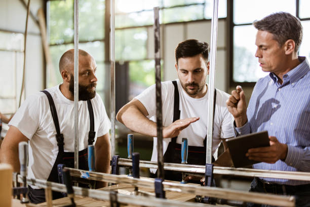 istock Young carpenters and their manager cooperating while in a workshop. 1182216304