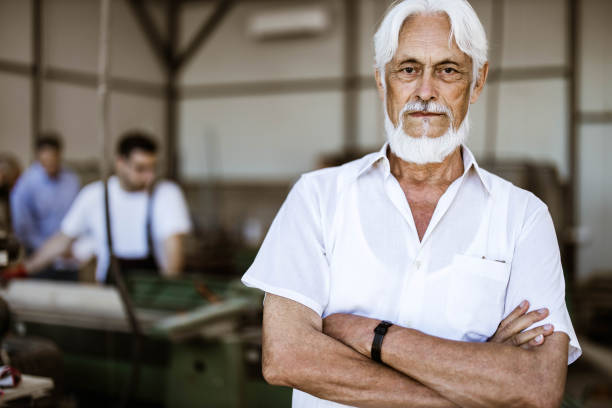 istock Confident senior manager with crossed arms in a workshop. 1182216351