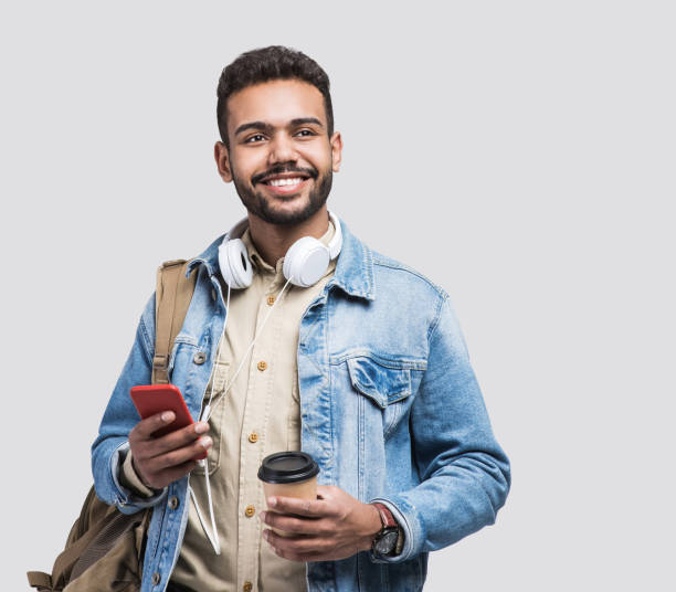 Portrait of happy man student going on a travel Studio shot of handsome smiling man using smartphone. one young man only stock pictures, royalty-free photos & images