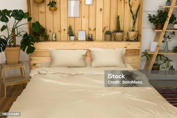 Real Photo Of A Botanical Bedroom Interior With Wooden Shelves Double Bed And Plants Bedroom Wooden Interior With Plants Next To A Bed Made With Pillows Stock Photo - Download Image Now
