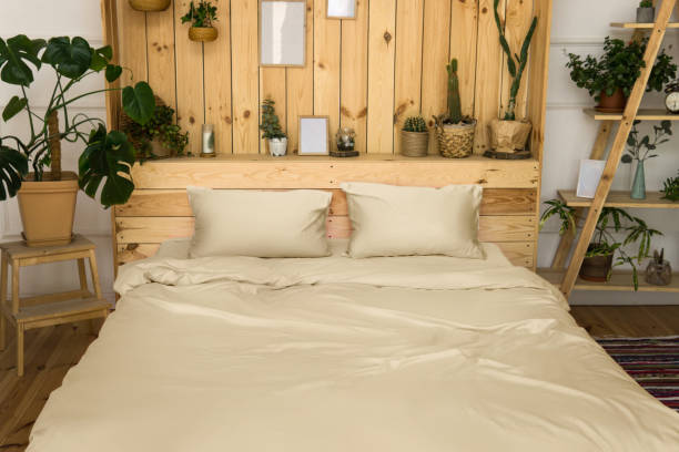 real photo of a botanical bedroom interior with wooden shelves,  double bed and plants. bedroom wooden interior with plants next to a bed made with pillows. - headboard imagens e fotografias de stock