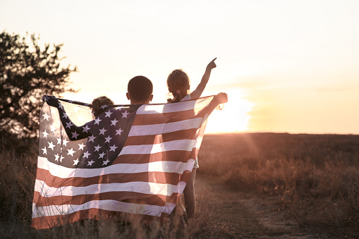 A happy family with an American flag at sunset.