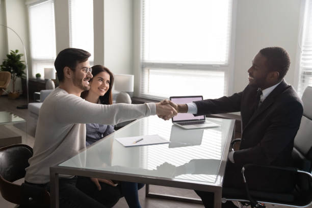 happy young couple shaking hands with african american financial advisor. - lawyer family talking discussion imagens e fotografias de stock