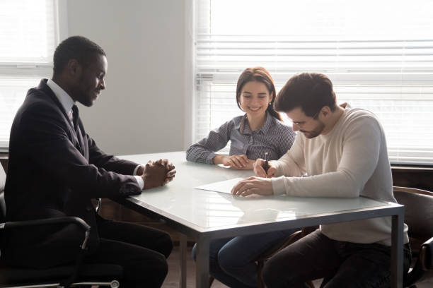 istock Smiling salesman watching happy clients signing contract. 1182227791