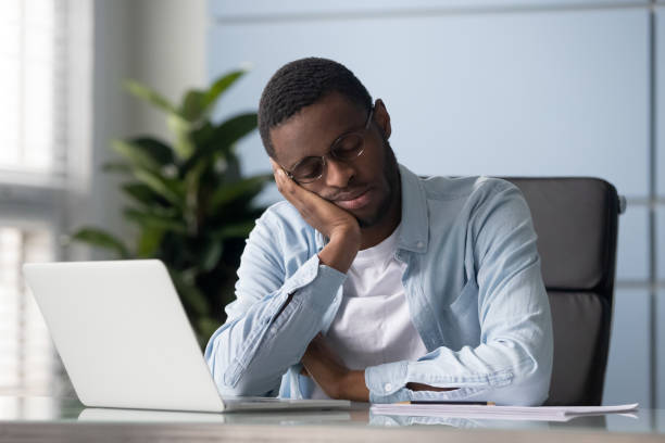 istock Exhausted young african american employee sleeping at workplace. 1182227851