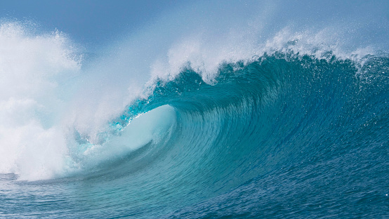 CLOSE UP: Beautiful deep blue tube wave in the wild Pacific Ocean curls towards a remote tropical island on a sunny day in summer. Spectacular shot of wild barrel wave coming from the exotic sea.