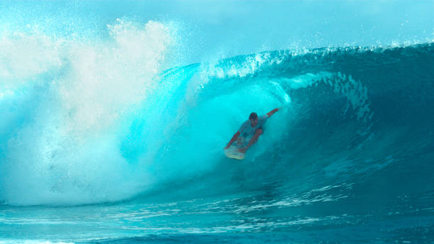 istock CLOSE UP: Surfboarder rides and drags his hand along a beautiful glassy wave. 1182231778